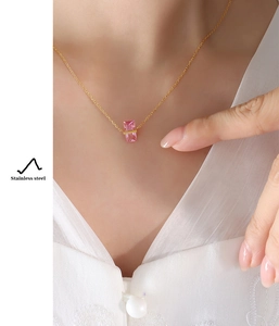 Macro close-up of a pink crystal pendant on a gold stainless steel chain worn by a model