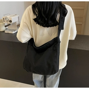 Minimalist black canvas tote bag shown on model in a cafe, large capacity for commuting