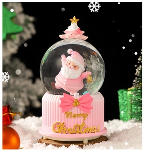 Close-up of pink Christmas snow globe with resin figurines and golden Merry Christmas text