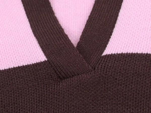 Dettaglio del collo a V e motivo a righe rosa e marrone su polo in maglia intrecciata