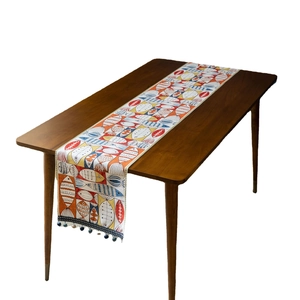 Colorful jacquard fish pattern table runner with tassels on dark wooden table