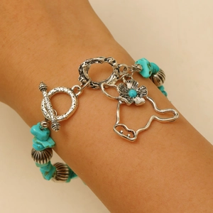 Detail shot of bohemian turquoise beaded bracelet with floral and dog silhouette charms