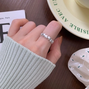 Detail of minimalist 925 sterling silver heart chain ring on hand with lifestyle setting