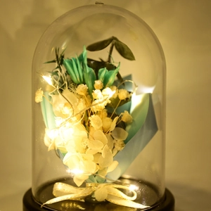 Close-up of LED lit preserved flower bouquet in a glass dome with warm lighting