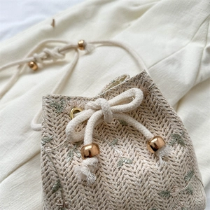 Beige woven bucket bag with green leaf embroidery and drawstring cotton shoulder strap