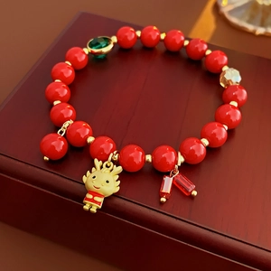 Détail du bracelet en perles rouges avec pendentif dragon doré en émail et pierre verte