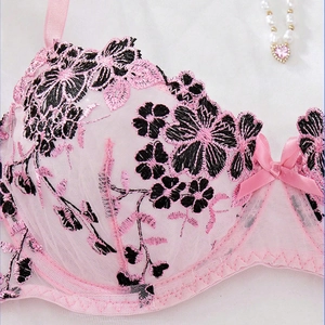 Close-up of floral embroidery on pink mesh lace bra with silk bow and pearl accents