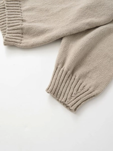 Macro shot of wide ribbed cuffs on a beige knitted sweater with high quality soft texture