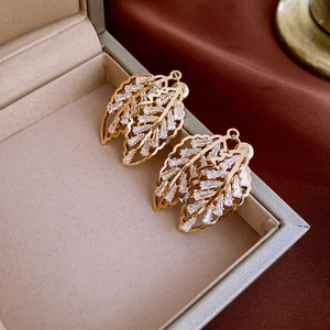 Gros plan sur les boucles d'oreilles feuille dorée avec zircons dans un coffret bijoux
