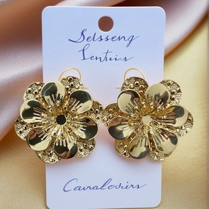 Exaggerated vintage gold flower stud earrings with layered petal texture on silk background