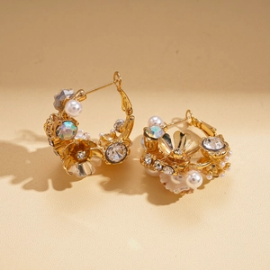 Close-up of golden floral earrings with white pearls and multicolor rhinestones