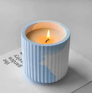 Scented candle in blue and white marble textured ceramic container with vertical stripes