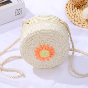 Detail of round beige woven straw crossbody bag with daisy embroidery for girls