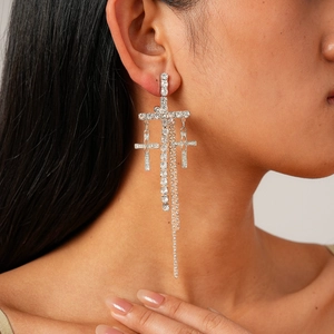 Sparkling silver cross tassel drop earrings with crystals on a female model