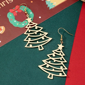 Close-up of golden hollowed-out Christmas tree earrings with star toppers on festive backdrop