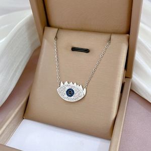 Macro view of silver evil eye necklace with blue crystal inlay in a jewelry box