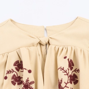 Beige long sleeve dress featuring intricate dark red floral embroidery and tie-neck detail