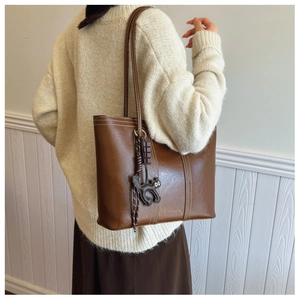 Brown leather tote bag with white stitching detail and black cat charm closeup