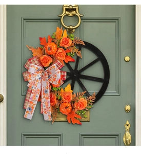 Detail of autumn wreath with orange pumpkins and maple leaves on a vintage wagon wheel