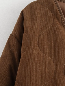 Detail van bruine corduroy stof met cirkelvormig gewatteerde stiksels en zachte textuur