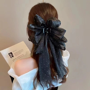 Detailed view of a large black mesh bow hair claw clip with elegant white polka dots