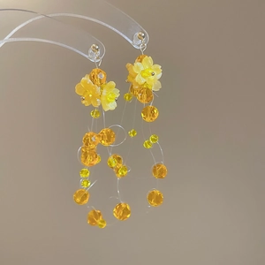 Detail view of yellow floral crystal tassel earrings with long beaded strands