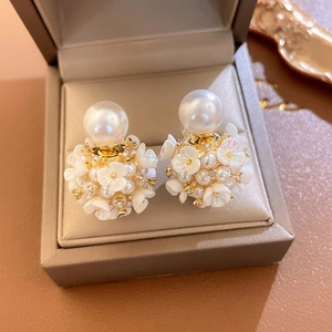 Détail macro de boucles d'oreilles fleur perle avec fleurs blanches et socle doré