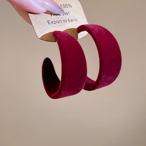 Détail de créoles en forme de C avec finition velours rouge foncé et tiges en argent