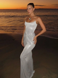 Abito lungo argento con paillettes e dettaglio nodo in vita sulla spiaggia al tramonto