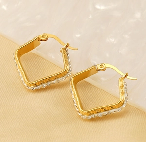 Macro shot of gold-plated square hoop earrings with micro-paved zircons and Greek key patterns