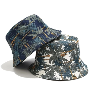 Détail de deux bobs réversibles en coton avec des imprimés de cocotiers tropicaux
