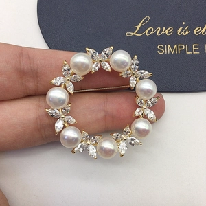 Macro shot of a wreath brooch with white pearls and zircons on a gold base