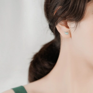 Close-up of blue whale sterling silver stud earrings worn on a female earlobe