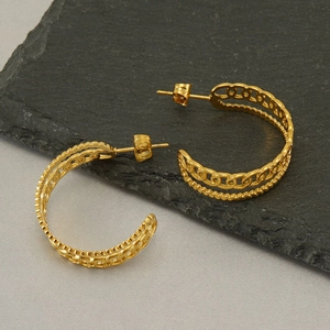 Golden double-row hollow earrings with chain and twist texture on a stone background