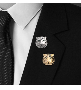 Close-up of gold and silver tiger head brooches with rhinestones on a black suit jacket