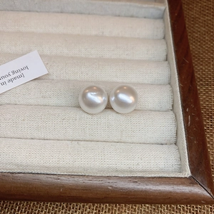 Elegant white pearl stud earrings on a velvet jewelry box with soft glossy finish