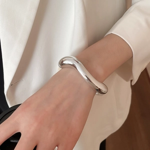 Fashionable chunky silver irregular wave bracelet with high-polish mirror finish on wrist