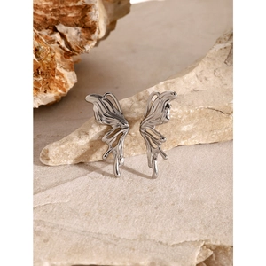 Y2K style butterfly stud earrings in silver stainless steel on natural stone background