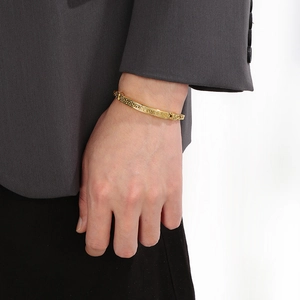 Close-up of golden stainless steel bracelet with Greek key pattern on male wrist