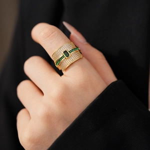 Close-up of gold ring with green square emerald and white pavé zircons on finger