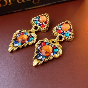 Macro view of vintage gold earrings with orange crystal and colorful bead embellishments