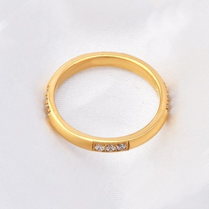 Detail of 18K gold plated titanium ring featuring twelve small clear crystals in a row