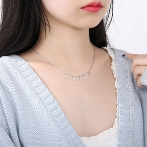 Detail of silver star and moon pendant necklace worn by a model in soft lighting