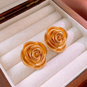 Detailed close-up of golden matte rose earrings placed in a luxury jewelry box padding