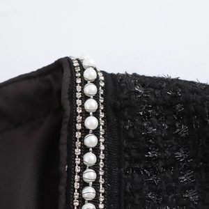 Detail des Karree-Ausschnitts mit Perlen- und Strassbesatz am schwarzen Tweed-Kleid