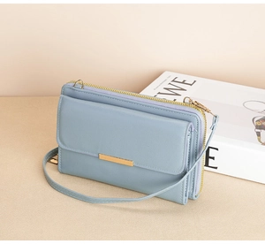 Detail view of light blue multi-layer long wallet with gold metal bar and thin shoulder strap