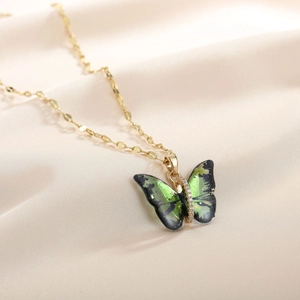 Elegant gold titanium necklace with gradient green butterfly pendant on silk background