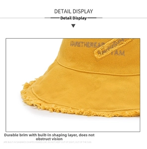 Detail view of yellow canvas bucket hat showing frayed edges and built-in shape wire