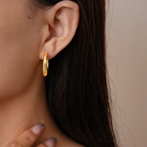 Detailed view of 18K gold plated geometric C-shape textured earrings on a model
