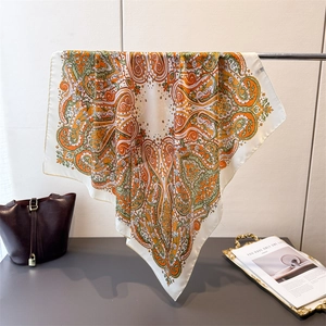 Detailed texture of paisley silk scarf hanging over a leather bucket bag and magazine